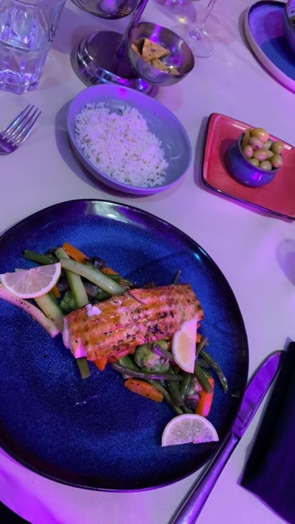 dining table with plate of salmon and vegetables