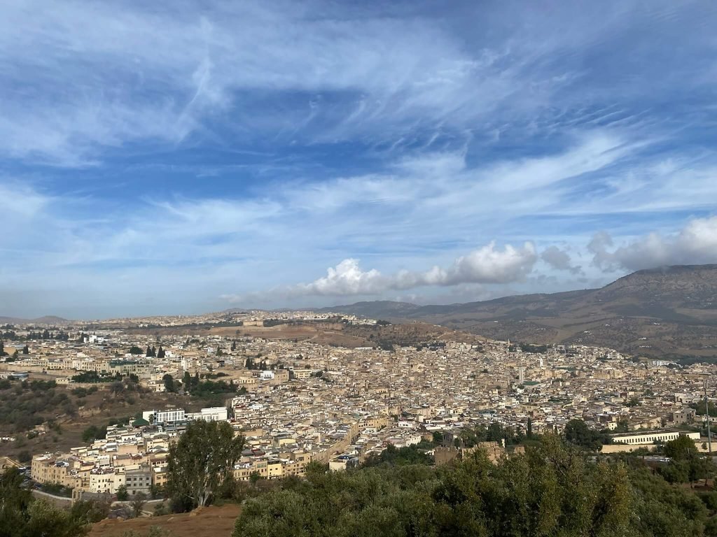 looking down onto Fes old town with mountains surrounding and blue sky