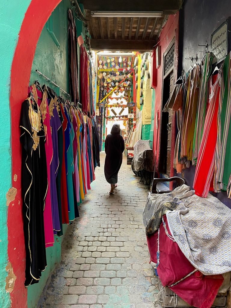 narrow medina street with loads of colourful dresses hanging