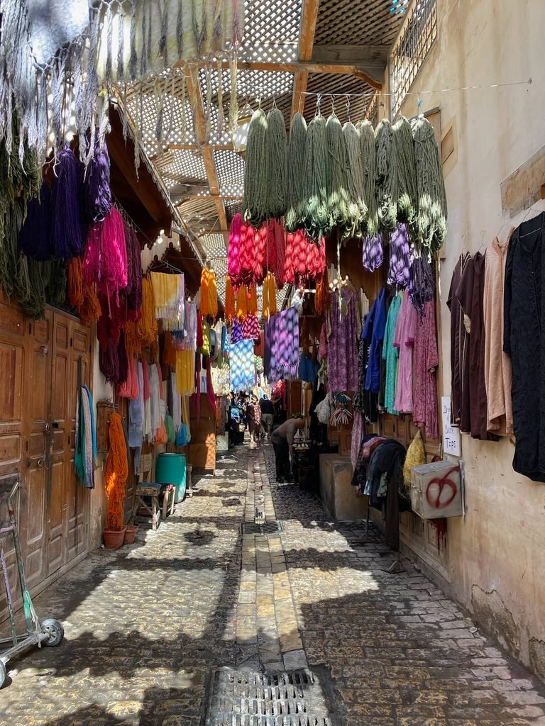 busy medina street with lots of clothing hanging for sale