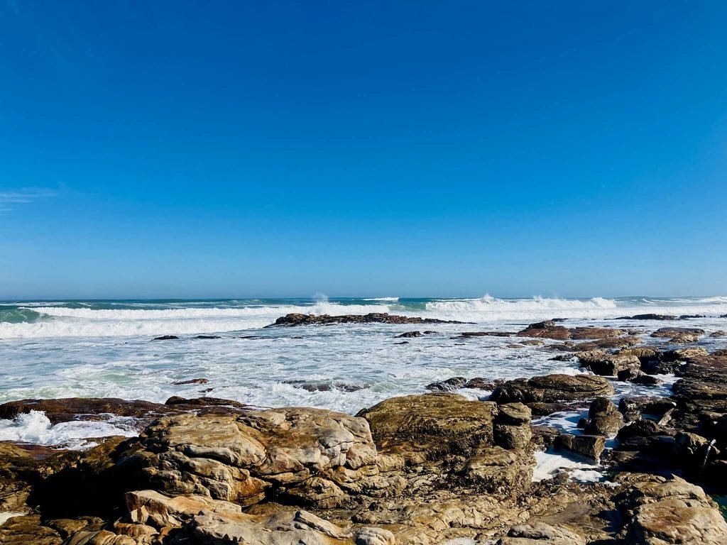 beautiful seascape, waves crashing on the rocks and bright blue sky