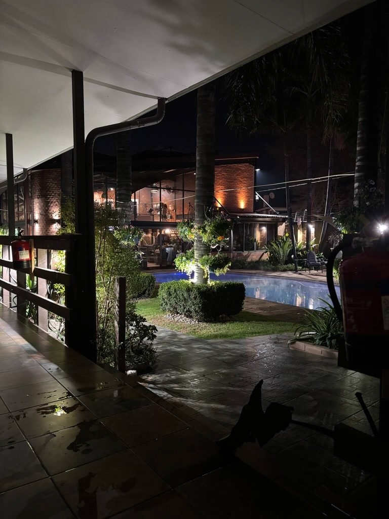 view of pool and gardens at hotel lit up at night